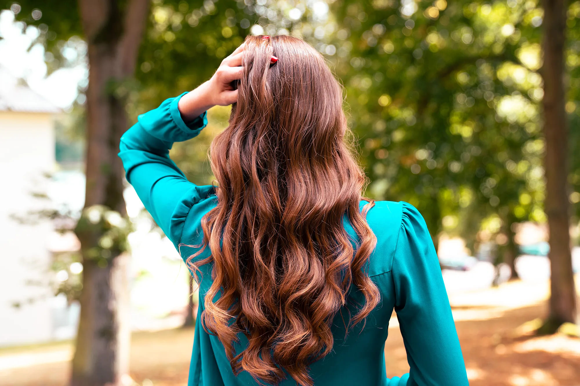Rückansicht einer Frau, die ihre braun-roten und lockigen, langen Haare zeigt